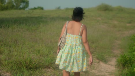 Mujer-Vestida-De-Verano-Caminando-Por-El-Campo-De-Hierba-Al-Atardecer,-Toma-Manual