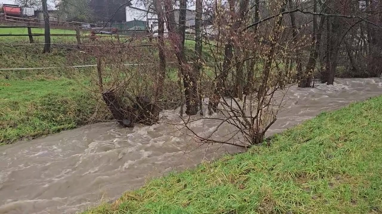 Kalná voda z rozvodněné řeky rychle proudící polem během povodně.