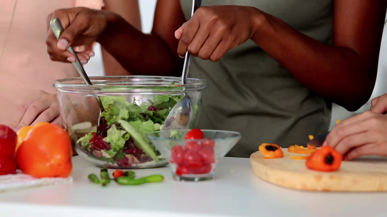 Women preparing food together while cutting vegetables