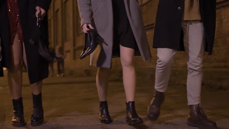 camera focuses on the feet of four friends walking in the street after the end of the year party 1