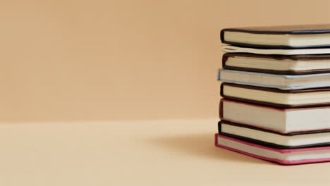 primer plano de una pila de libros con espacio de copia en un fondo beige, en cámara lenta