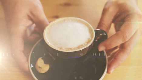 Animation-of-light-spots-over-hands-of-caucasian-man-holding-cup-of-coffee