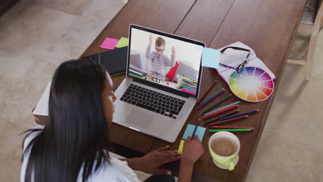 Caucasian-female-teacher-using-laptop-on-video-call-with-schoolboy,-making-notes