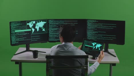 back view of asian man developer working with tablet while write code with multiple computer screens in green screen studio