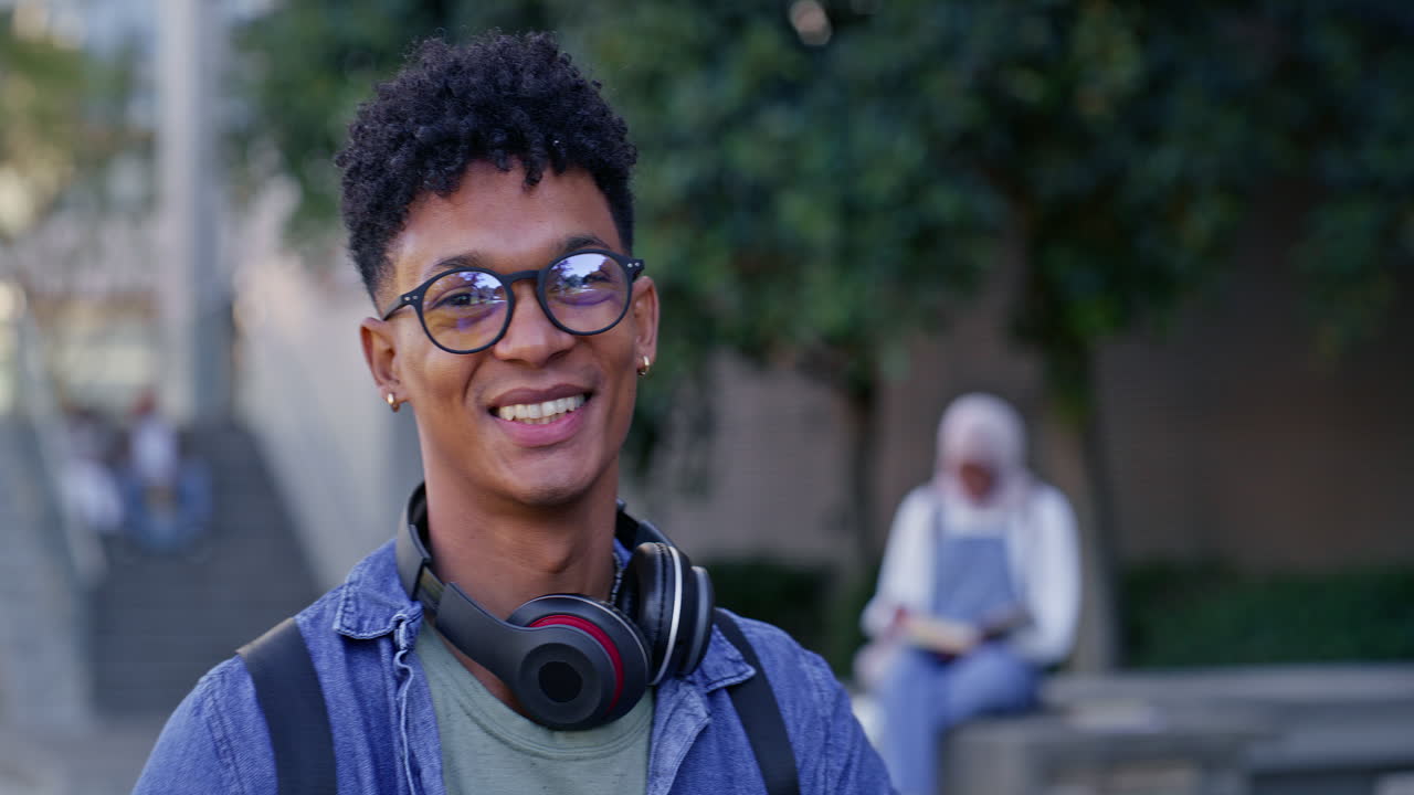 Portrait d'un étudiant souriant avec des lunettes et un casque audio