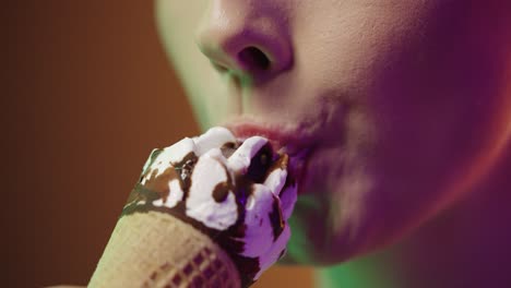 close up of a young woman eating a vegan cream ice cream with vegan chocolate and enjoying the delicious taste in front of black and yellow background in slow motion