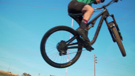 man on mountain bike launches over a dirt ramp in a bike park into the sky