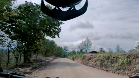 two bicyclists ride their bicycle on a road inside of a forest, hill, and village in guatemala, north america