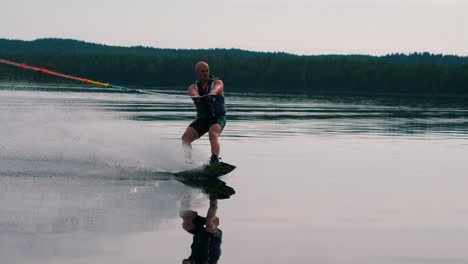 Primer-Plano-De-Un-Joven-Montando-Un-Wakeboard-Después-De-Un-Barco-Deportivo-En-El-Archipiélago-Sueco-En-El-Verano