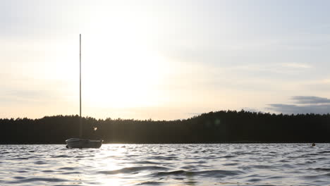 sunset on calm lake with sailboat