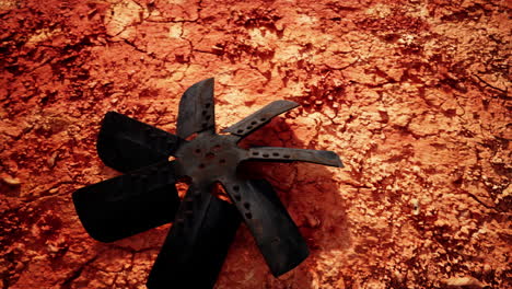 rusted metal fan on cracked red ground