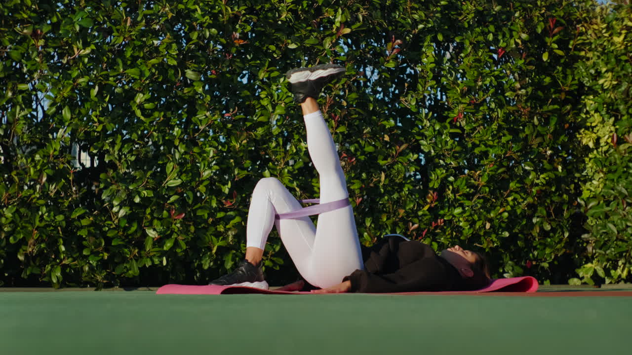 야외에서 저항 밴드로 다리 리프트를 하는 여성