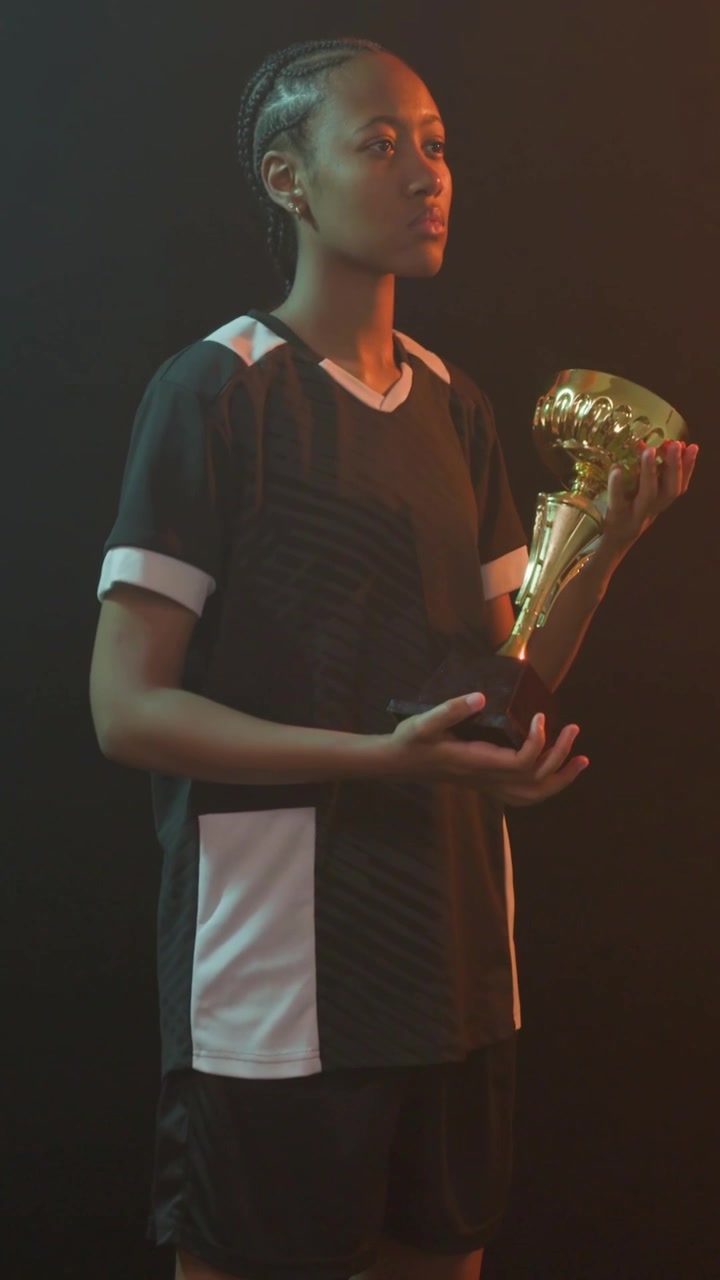 Video verticale: Giocatrice solleva un trofeo d'oro mentre la telecamera si allontana, mostrando un premio sportivo