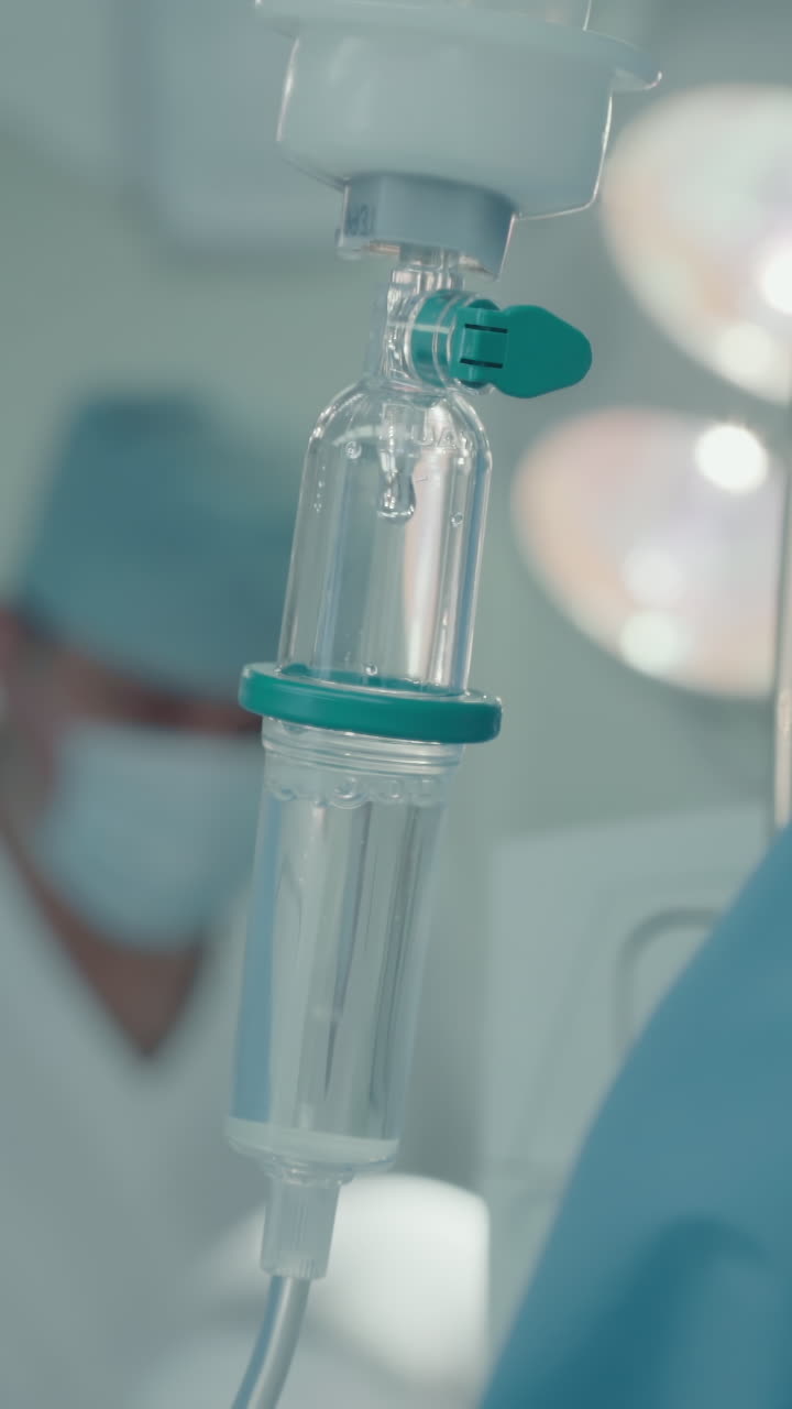 I.V. against anesthesiologist in room. Brightly lit state-of-art operating room equipped with latest medical technologies in modern hospital