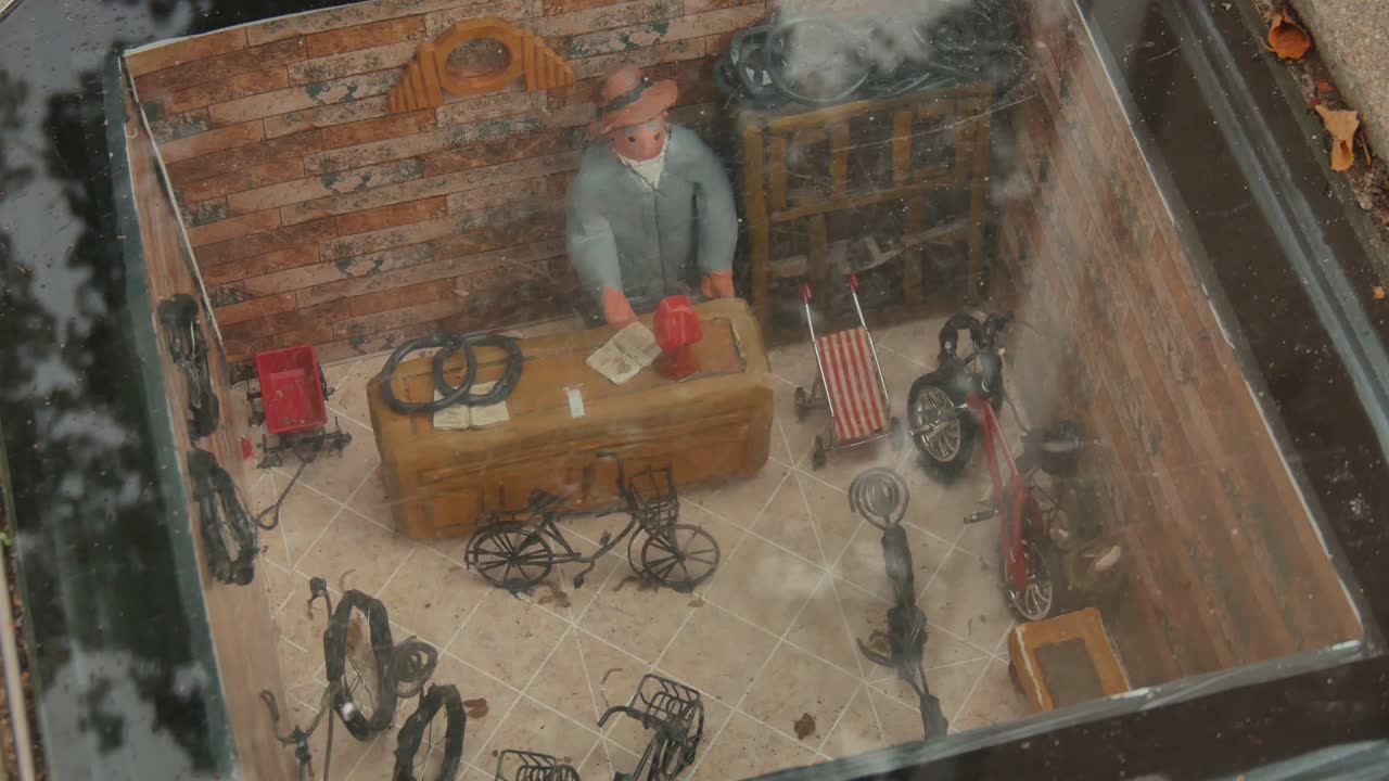 уменьшенное помещение мастерской по ремонту велосипедов, встроенное под стекло в покрытие пешеходной тротуарной дорожки