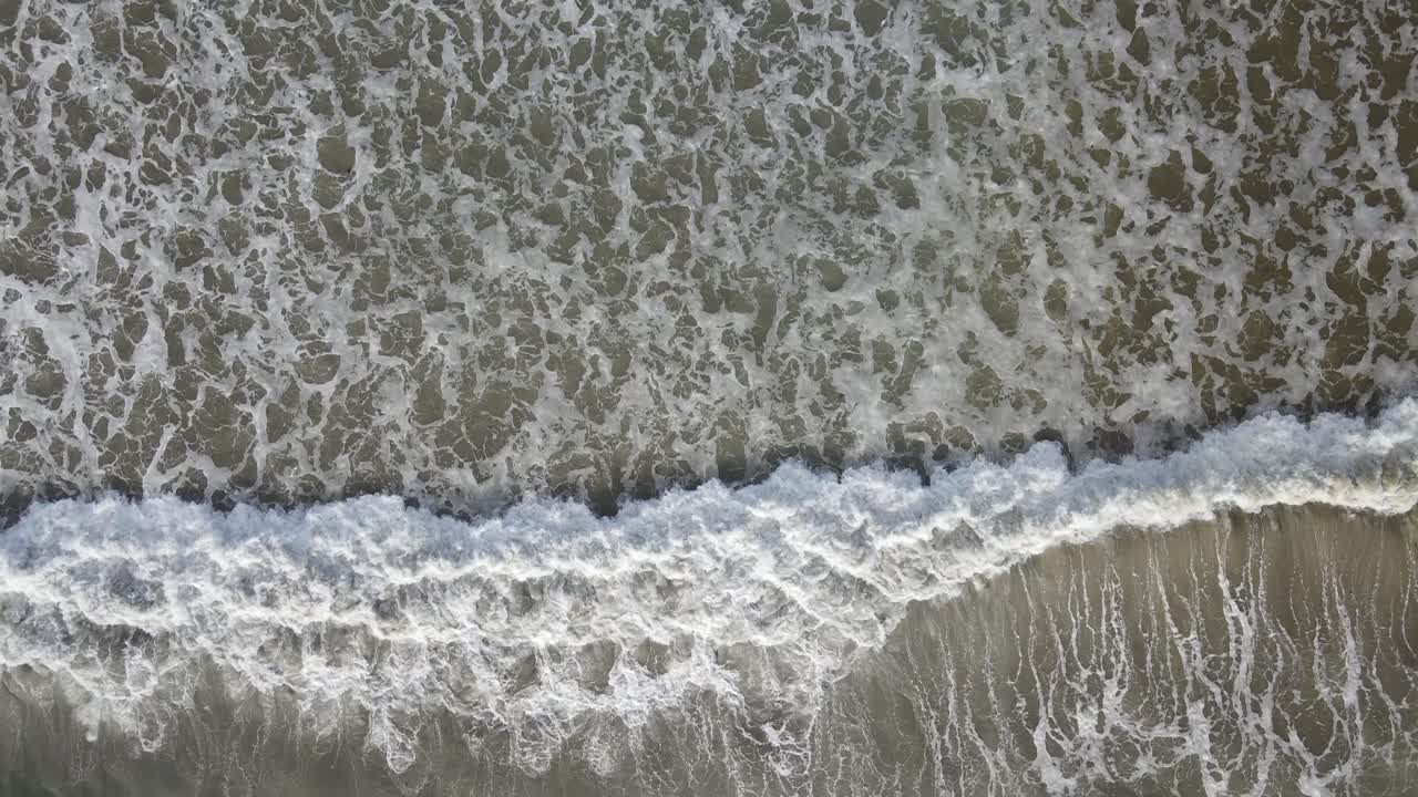 Amazing top-down view of waves rolling onto a beach