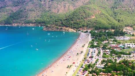 aerial view of adrasan beach on a hot summer day in turkey as people sun bathe while boats are anchored along the mountainous mediterranean coastline