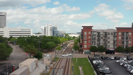 Aerial-view-of-empty-double-track-railway-line-leading-through-town.-Cars-driving-on-rail-crossing.-Forward-flying-drone.-Dallas,-Texas,-US