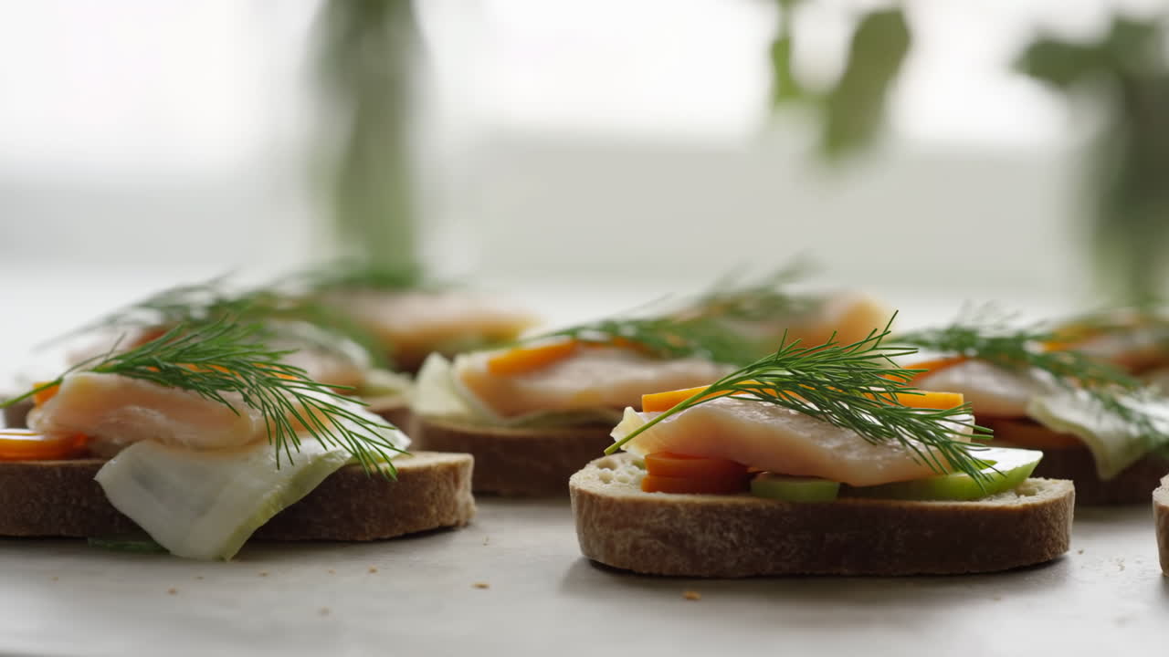 Gros plan d'un canapé au saumon fumé sur pain de seigle avec du fromage frais, des tranches de concombre et de l'aneth frais, lumière du matin.