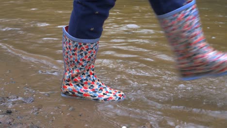 young child walking and splashing water in welly boots 2