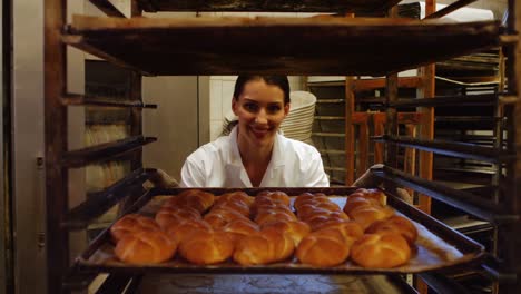 female baker putting baked michetta in baking trolley