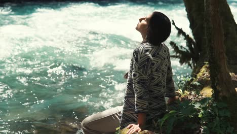 woman relaxing by a river in a forest