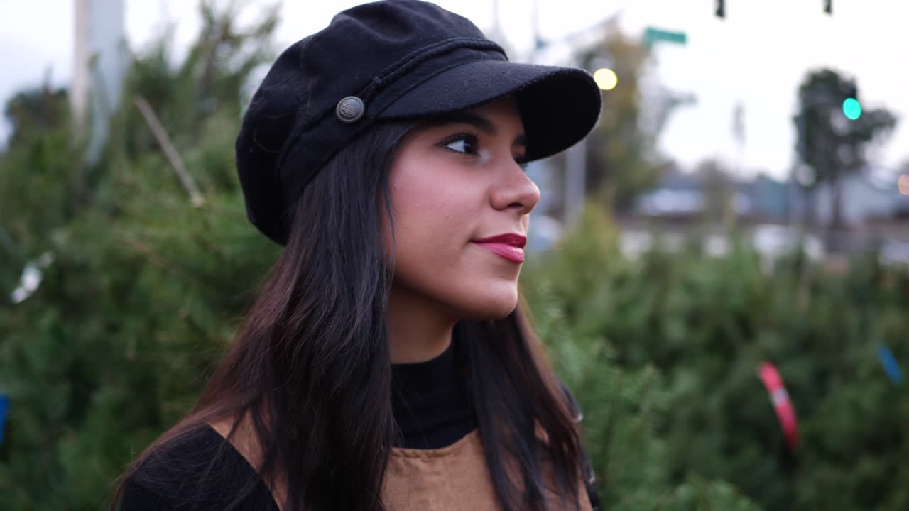 una mujer joven comprando en un lote de árboles de navidad con coníferas verdes de abeto douglas en un vivero botánico de vacaciones