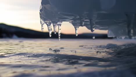 water droplets fall gracefully from the underside of a boat as the sun sets over a tranquil lake. the gentle ripples reflect the warm colors of the horizon, creating a peaceful atmosphere.