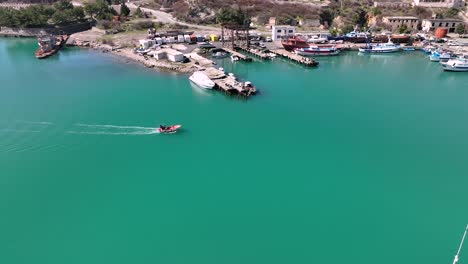 Pan-Aéreo-De-Lancha-Entrando-En-El-Puerto-Con-Agua-Verde-Y-Grandes-Barcos