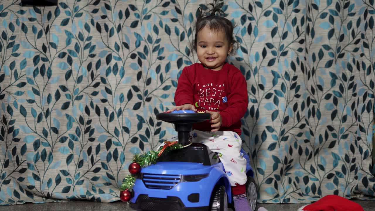 un bebé lindo disfrutando de la celebración de la víspera de navidad con un regalo de coche para el niño en casa por la noche