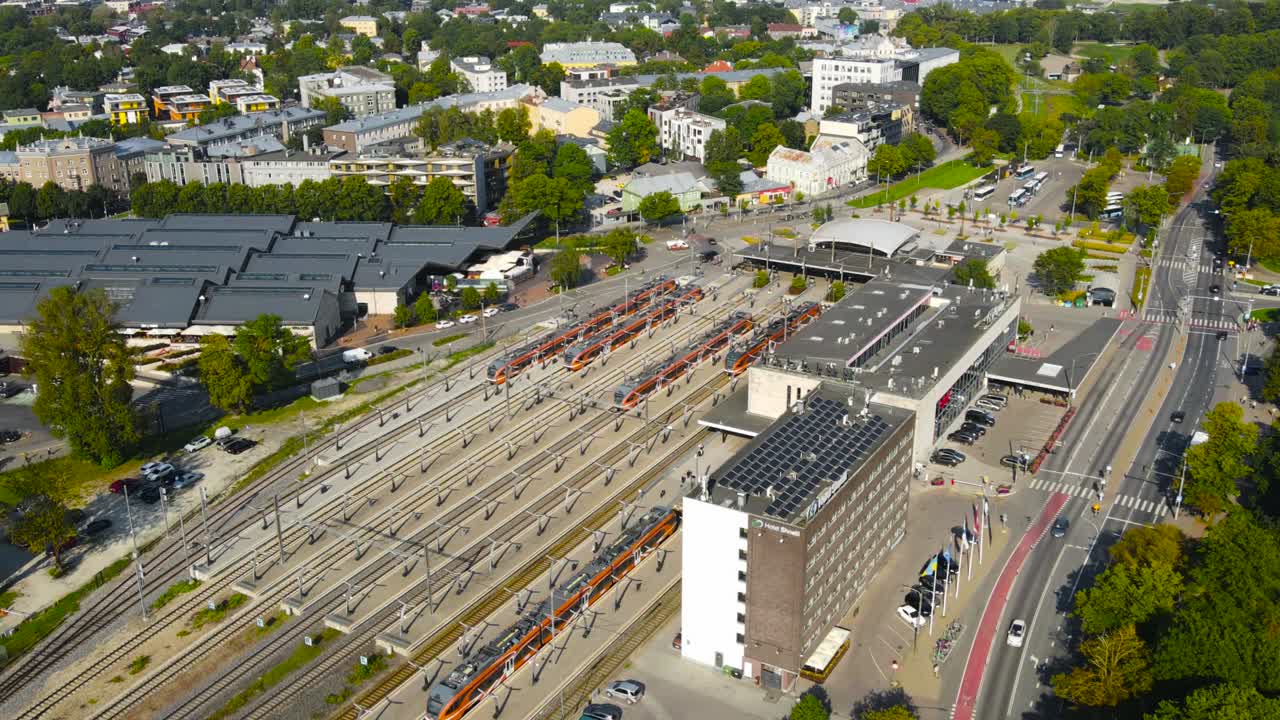 Aerial drone hyperlapse or timelapse footage orbiting above Balti Jaam train or railway station where electrical trains are parked and driving from. Passengers walking on and off the trains, Summer