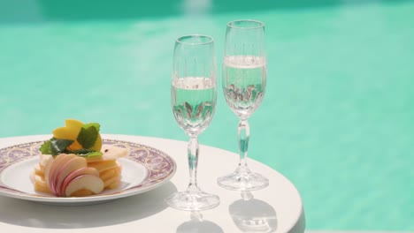 white champagne wine glass and gourmet food with swimming pool on background