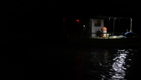 un pescador recoge sus redes de un pequeño barco de pesca en la oscuridad de la noche