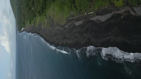 waves from the ocean rooling on black sand beach