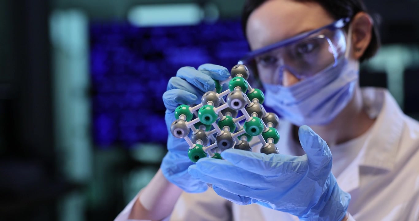 Woman chemistry scientist studies molecular model in laboratory