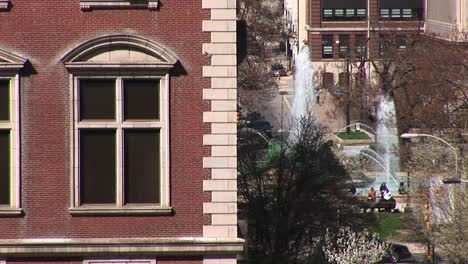 Ein-Blick-Auf-Einen-Innenstadtpark-Mit-Springbrunnen-Mit-Einer-Klassischen-Altbauecke-Im-Vordergrund