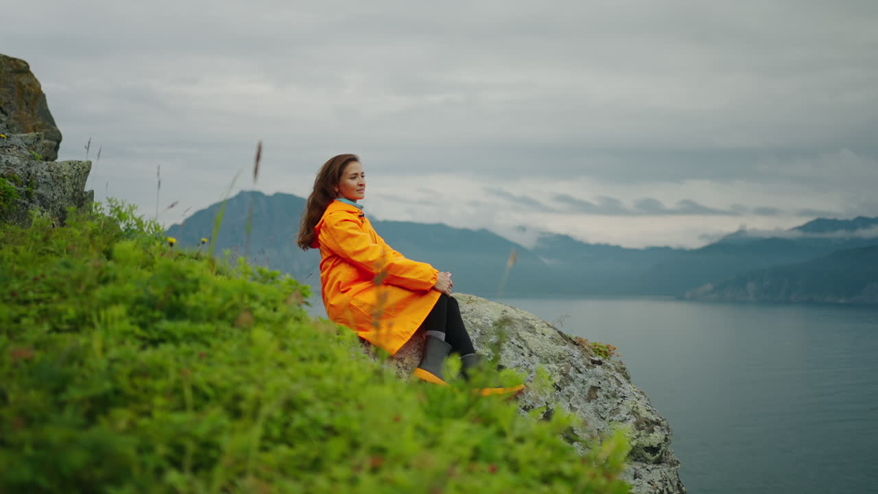 Woman in Orange Raincoat by the Lake