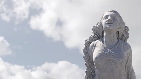 animation of gray sculpture of woman over blue sky and clouds, copy space