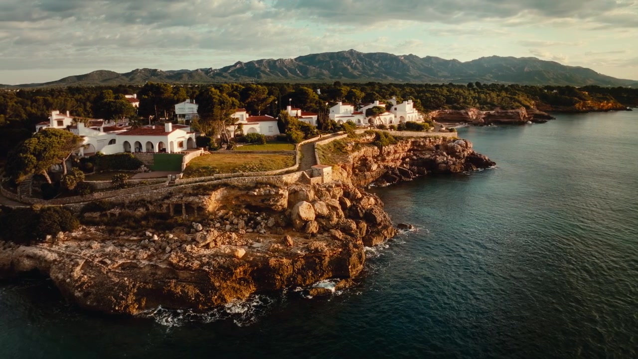 Fantastisk 4K droneoptagelse fra luften af en luksusejendom på en barsk kystlinje, krystalklart blåt vand. Perfekt til rejse-, natur-, luksus- og filmproduktioner.