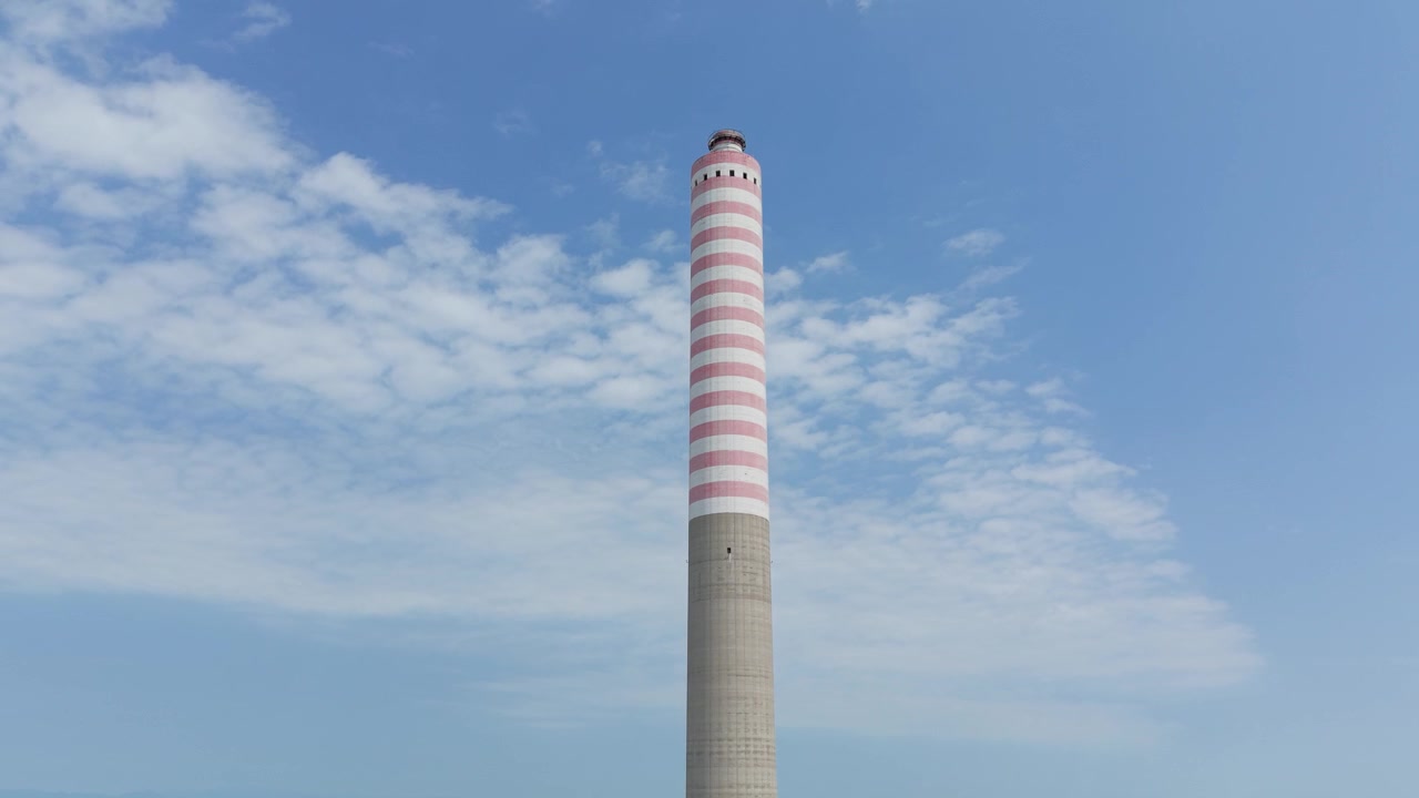 Veduta aerea di un'alta ciminiera di una centrale elettrica contro il cielo nel Nord Italia, che rappresenta l'infrastruttura industriale, la produzione di energia e i servizi pubblici su larga scala.