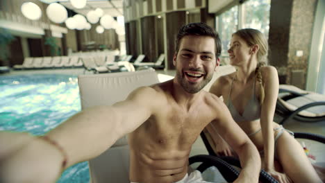 portrait of cheerful couple posing for selfie video near swimming pool.