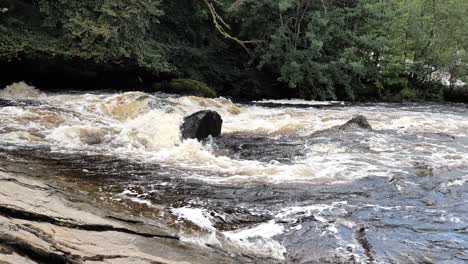 inundación y fuerte corriente con espuma blanca del río dochart cerca de killin, escocia, reino unido