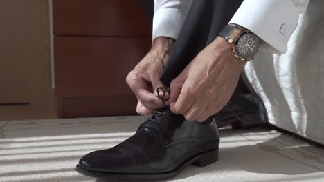 businessman ties shoelace by his bed