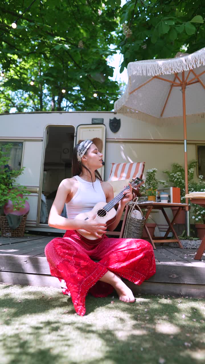 Donna che suona l'ukulele all'aperto in un campeggio