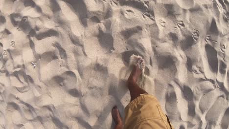 black feet walking across sandy beach, looking down point of view