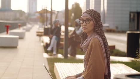 woman with laptop posing on bench