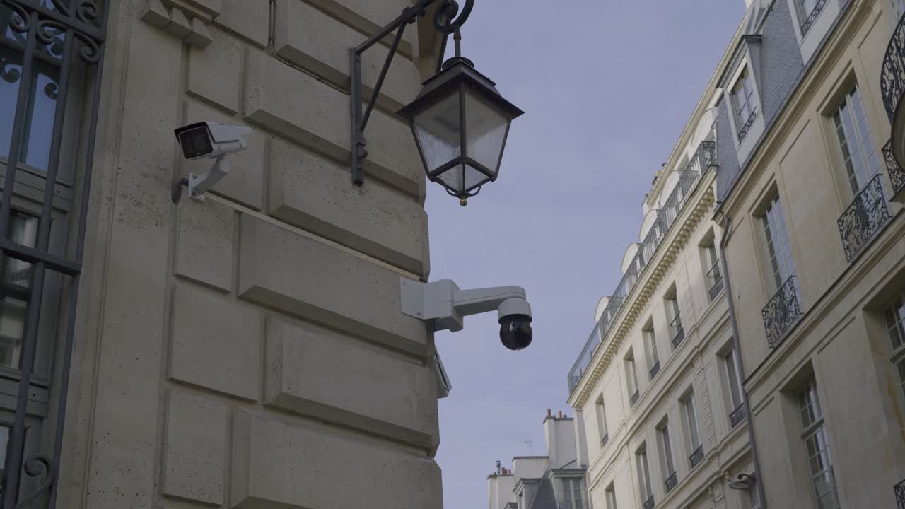 Surveillance cameras on the corner of a building in Paris with a clear blue sky