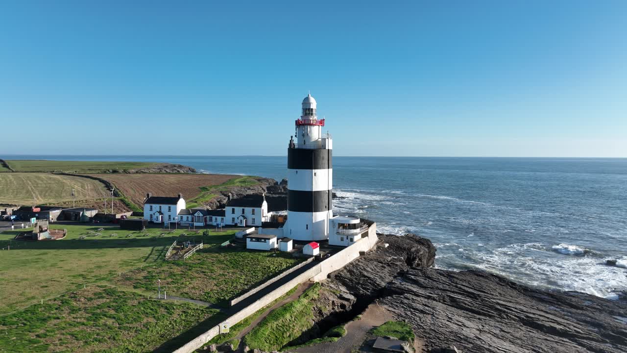 Faro di Hook Head, Wexford, Irlanda: lento movimento aereo all'indietro nel punto in cui l'Atlantico selvaggio incontra la terra