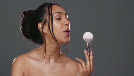 Woman,-blowing-powder-from-brush-for-makeup