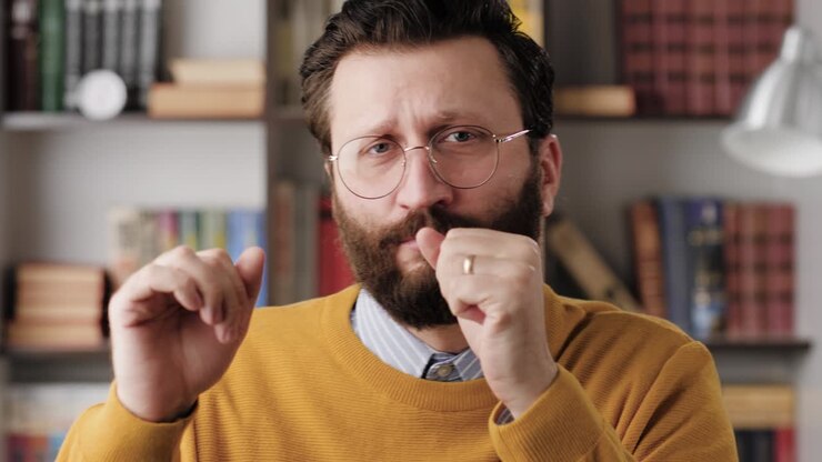 Man is dancing. Positive bearded man office worker in glasses in office or apartment room looking at camera and dances and sings along. Close-up and slow motion